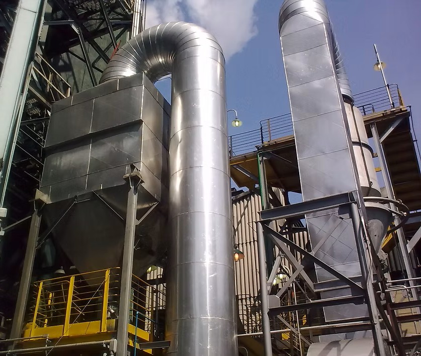 Ciclones e multiciclones industriais para separação sólido-gás, com corpos cilíndricos metálicos e funis de descarga cônicos, instalados em planta industrial para captação de particulados.