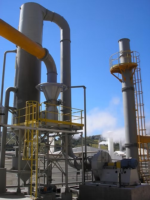 Sistema de lavagem de gases industrial composto por torre de tratamento vertical, duto de entrada de ar amarelo, exaustor centrífugo acoplado a motor elétrico e chaminé de exaustão com plataforma de acesso e escada tipo marinheiro.