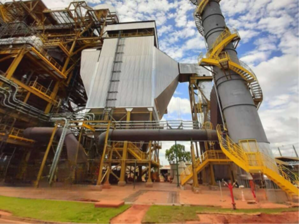 Vista externa de unidade industrial com precipitador eletrostático de estrutura metálica vertical, integrado a rede de dutos e torre de exaustão cilíndrica com escadaria de acesso em espiral.